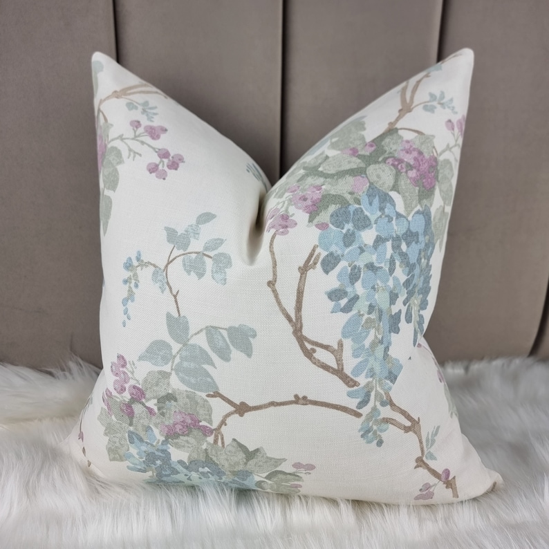 May include: A white pillow with a floral pattern in shades of blue, green, and pink. The flowers are arranged in a delicate, whimsical design.