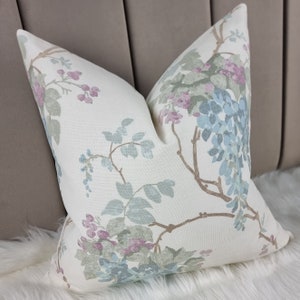 May include: A white pillow with a floral pattern featuring blue, green, and pink flowers on a beige background.