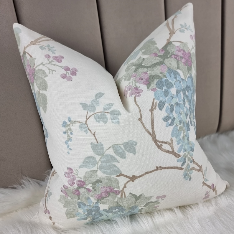 May include: A white pillow with a floral pattern featuring blue, green, and pink flowers on a beige background.