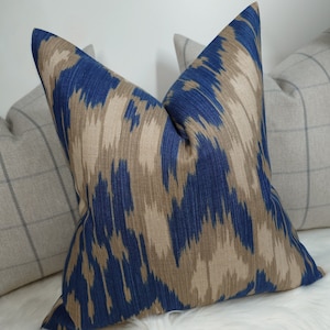 May include: A blue and brown patterned throw pillow with a geometric design. The pillow is made of a soft, textured fabric.