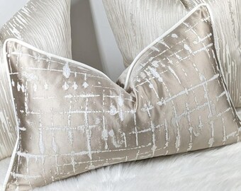 May include: Two decorative throw pillows with a white and beige geometric pattern. The pillows have a white piping trim.