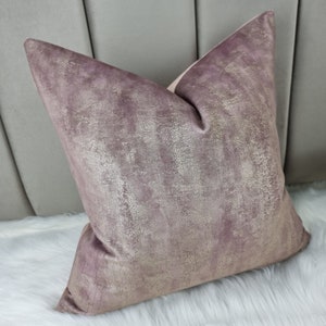 May include: A soft, plush cushion with a textured, metallic finish in a dusty rose colour. The cushion is made of velvet and has a subtle shimmer.
