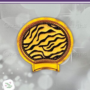 May include: Gold cup with a black and gold zebra print design. The cup has a rounded top and a flat bottom. It is designed to fit over a standard cup.