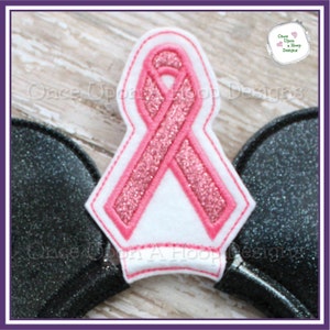 Puede incluir: Diseño de bordado de cinta rosa con purpurina para una diadema u otro proyecto artesanal. El diseño está sobre un fondo blanco y presenta una cinta rosa con purpurina.