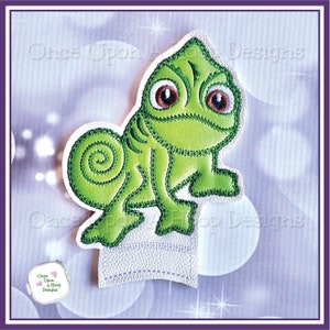 Może przedstawiać: Zielona haftowana aplikacja kameleona na białym tle. Kameleon ma zwinięty ogon i duże brązowe oczy. Tekst "Once Upon A Hoop Designs" jest widoczny na tle.