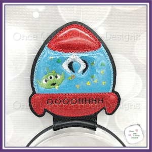 Puede incluir: Un parche bordado de una nave espacial con un extraterrestre verde en su interior. La nave espacial es roja, azul y verde, tiene una cúpula de plástico transparente y el texto "OOOOHHHH" está bordado en la parte inferior.