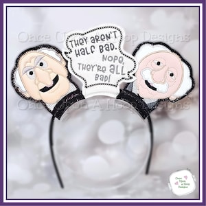 Pode incluir: Uma tiara preta com duas faces de personagens e um balão de fala. O balão de fala diz: "Eles não são tão ruins. Não, eles são todos ruins!" Os personagens têm cabelo branco e contornos pretos, em uma faixa de plástico transparente.