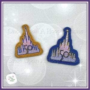 May include: Two embroidered patches of a pink castle with gold trim. The castle is shaped like a famous theme park castle. The number 50 is embroidered in gold on the front of each patch. One patch is on a yellow background and the other is on a blue background.