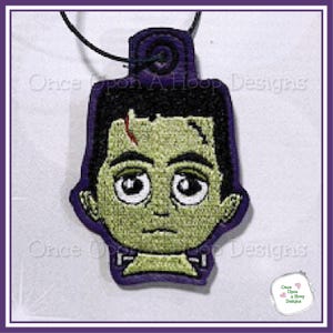 May include: A Frankenstein's monster-themed embroidered patch with a purple border. The patch features a green-skinned monster with black hair, large eyes, and a scar. The text "Once Upon A Hoop Designs" is visible.