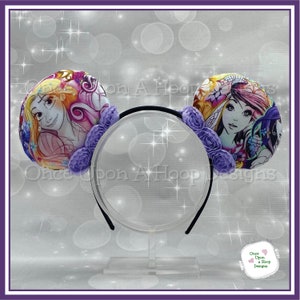May include: Purple flower headband with two round ears featuring a colorful illustration of Rapunzel and a mermaid. The headband is on a white stand.