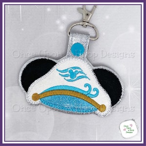 May include: A silver glitter keychain with a blue and white captain's hat with a Mickey Mouse ear design and a gold trim. The hat has a blue and white wave design with a Mickey Mouse head in the center. The keychain has a silver loop and a silver clasp.