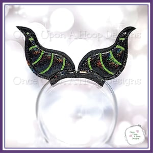 May include: Black and green headband with a pair of devil horns. The horns are made of a sparkly fabric with green accents.