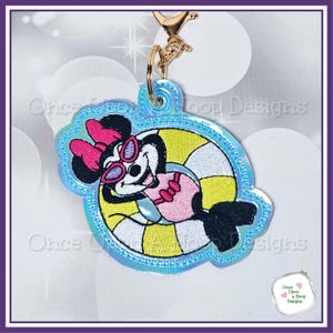 May include: A blue and white iridescent keychain featuring a cartoon mouse wearing sunglasses and a pink swimsuit, floating on a yellow and white striped inner tube.
