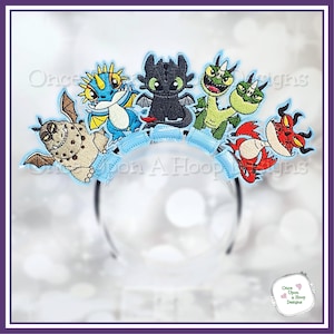 May include: A black headband featuring embroidered cartoon dragons in various colors. The dragons are blue, black, green, red, and brown, with a light blue decorative band. The text "Once Upon A Hoop Designs" is visible.