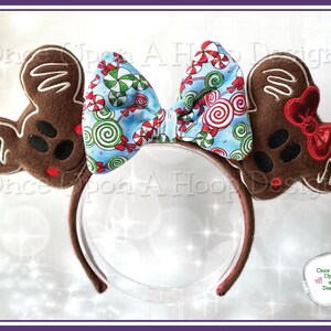 May include: A pair of gingerbread mouse ears with a red and white candy cane bow. The bow is decorated with green and white candy canes and swirls. The ears are brown and have a white outline. The headband is red.