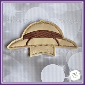 May include: A brown and beige felt applique of a safari hat with a brown brim. The hat is stitched with a decorative stitch around the brim and crown.