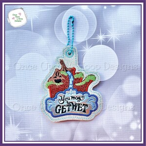 May include: A blue and green embroidered patch with a cartoon image of a water ride and the text "You may get wet". The patch has a blue chain attached to the top.
