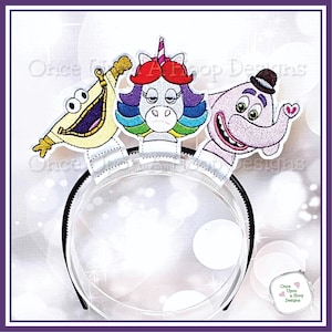 May include: A clear plastic headband with three character appliqués: a yellow banana, a unicorn with rainbow hair, and a pink elephant wearing a bowler hat. The appliqués are embroidered with detailed stitching and vibrant colors.
