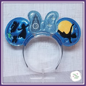 May include: Blue and yellow Mickey Mouse ears with a silhouette of Peter Pan and Tinkerbell flying in front of Cinderella's castle and the moon.