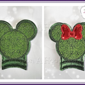 Könnte beinhalten: Grüne Filz-Kopfformen von Mickey Mouse und Minnie Mouse mit einem Wirbelmuster. Minnie Mouse hat eine rote Schleife.