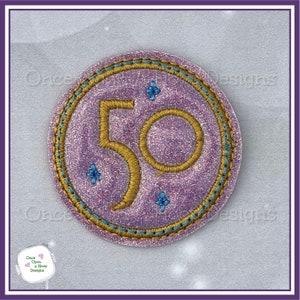 Peut inclure: Un patch brodé de couleur violet et or avec le chiffre 50 au centre. Le patch est entouré d'une bordure bleue et or et comporte quatre petites étoiles bleues.