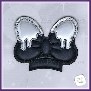 May include: Black and white felt bow with a silver glitter outline. The bow has a dripping effect, with white felt dripping down the sides.