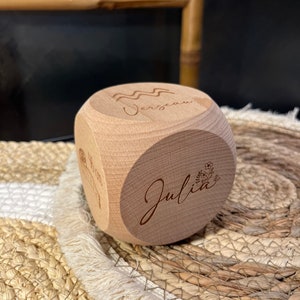 Peut inclure: Un cube en bois avec le nom "Julia" et le signe astrologique Verseau gravé dessus. Le cube est posé sur un tapis tissé.