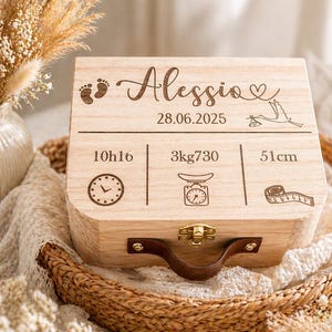 Peut inclure: Coffret souvenir en bois clair avec le nom "Alessia" gravé, ainsi que des empreintes de bébé, une cigogne et des détails de naissance. Le coffret a une poignée en cuir marron et un fermoir doré.