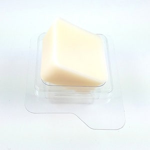 May include: A white wax melt in a clear plastic container. The wax melt is shaped like a triangle.