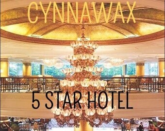 May include: A luxurious hotel lobby with a large, ornate chandelier hanging from the ceiling. The text "CYNNAWAX 5 STAR HOTEL" is displayed on the wall. The floor is tiled with a marble pattern and there is a floral arrangement in the center of the lobby.