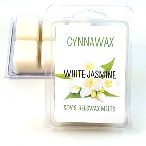Puede incluir: Un paquete de cera de soja y cera de abeja blanca con una etiqueta que dice "Cynnawax White Jasmine Soy & Beeswax Melts". La etiqueta presenta una flor de jazm&iacute;n blanca.