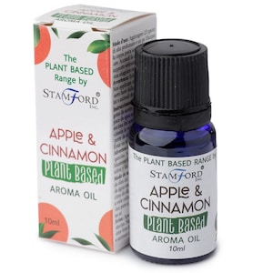 Könnte beinhalten: Aromaölflasche und -box mit der Aufschrift "Apple & Cinnamon Plant Based Aroma Oil". Die Flasche ist dunkelblau mit schwarzem Deckel. Die Box ist weiß mit roten Apfelillustrationen und grünem Text.