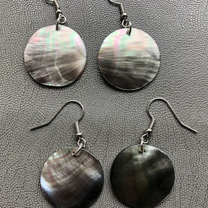 May include: A pair of silver hoop earrings with round black and iridescent shell pendants.