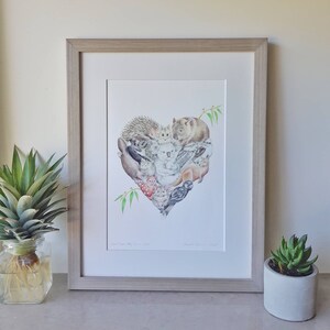 May include: A framed print of a heart-shaped illustration featuring various Australian animals, including a koala, wombat, echidna, and birds. The print is titled "Our Fauna, Our Home" and signed by the artist.