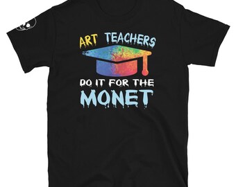 Puede incluir: Camiseta negra con un diseño gráfico colorido. El diseño presenta un birrete con colores del arcoíris y el texto "ART TEACHERS DO IT FOR THE MONET" en blanco y amarillo.