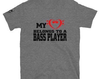 Puede incluir: Camiseta gris jaspeado con el texto "MY BELONGS TO A BASS PLAYER" en letras negras. La palabra "MY" está encima de una clave de sol roja en forma de corazón. Un pequeño gráfico de calavera está en la manga izquierda.