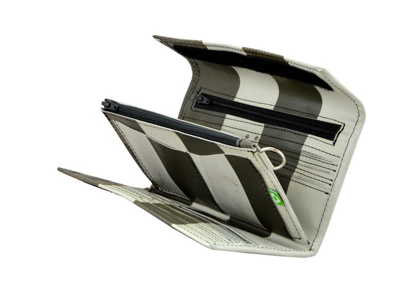 May include: A black and white striped wallet with a zipper closure and multiple compartments. The wallet is made from recycled materials and has a green logo.