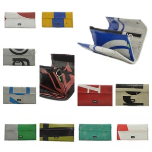 May include: A collection of 10 wallets made from recycled materials. The wallets are in various colours and patterns, including red, blue, green, yellow, and black. Each wallet has a small green tag with the word "RECYCLED" on it.