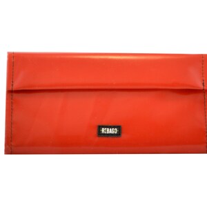 May include: A bright red wallet with a black "REBAGO" label.