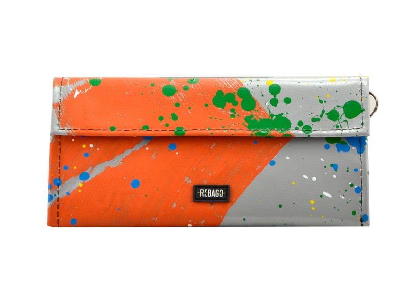 May include: A grey and orange wallet with a splatter paint design. The wallet has a black label that says "REBAGCO".