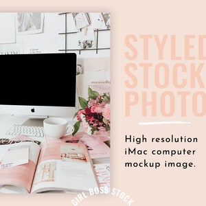 Puede incluir: Un ordenador iMac blanco con una pantalla negra está sobre un escritorio blanco. Hay revistas, una taza de café blanca y un ramo de flores rosas y rojas sobre el escritorio. El fondo es una pared blanca con una rejilla de alambre negra con fotos y notas.