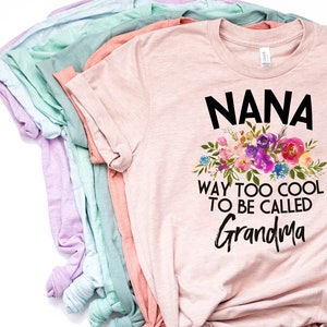 Puede incluir: Camiseta rosa con un dise&ntilde;o floral y el texto "NANA WAY TOO COOL TO BE CALLED GRANDMA".