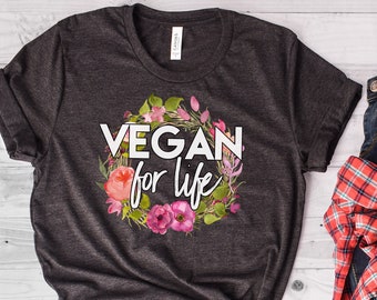 May include: A dark grey t-shirt with a white floral wreath and the text "VEGAN for life".
