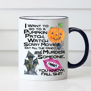May include: White ceramic coffee mug with a black rim and handle. The mug features a Halloween-themed design with a pumpkin, a haunted house, and a pair of lips with fangs. The text on the mug reads "I want to go to a pumpkin patch, watch scary movies, eat all the candy and murder someone. You know, fall shit."