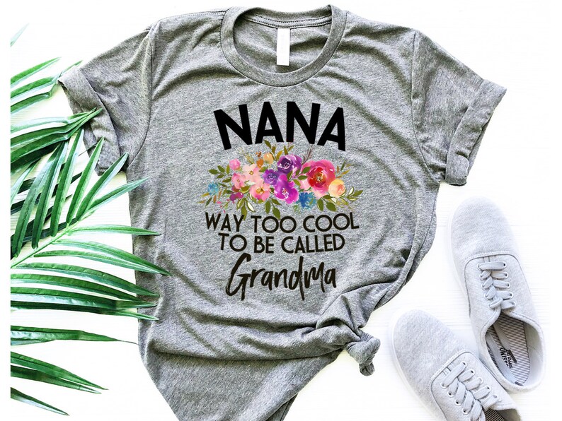 Puede incluir: Camiseta gris con un dise&ntilde;o floral y el texto "NANA WAY TOO COOL TO BE CALLED GRANDMA".