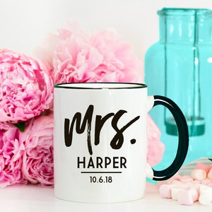 May include: White ceramic mug with a black rim and handle. The mug has black text that reads "Mrs. Harper 10.6.18".
