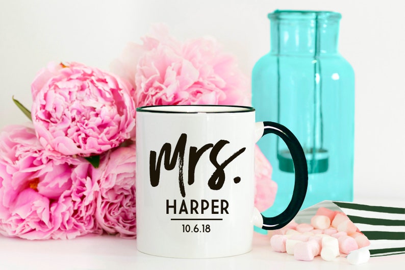 May include: White ceramic mug with a black rim and handle. The mug has black text that reads "Mrs. Harper 10.6.18".