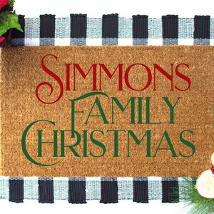 Puede incluir: Una alfombra de coco marr&oacute;n con el texto "Simmons Family Christmas" en letras rojas y verdes. La alfombra est&aacute; sobre una alfombra a cuadros negros y blancos.