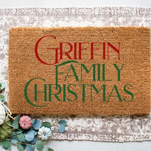 Puede incluir: Una alfombra de coco marr&oacute;n con el texto "GRIFFIN FAMILY CHRISTMAS" en letras verdes y rojas.