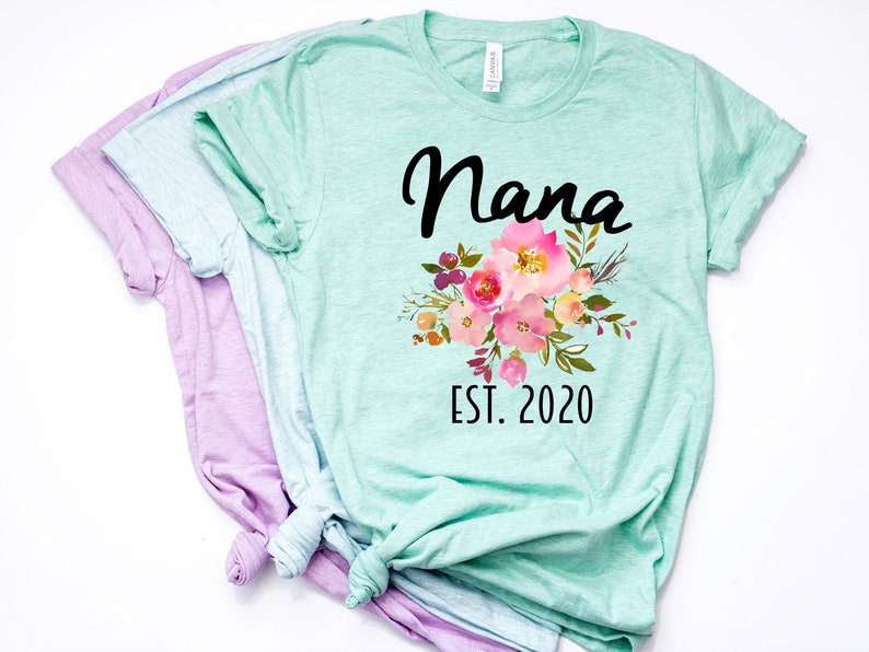Puede incluir: Una camiseta verde claro con un dise&ntilde;o floral y el texto "Nana Est. 2020".
